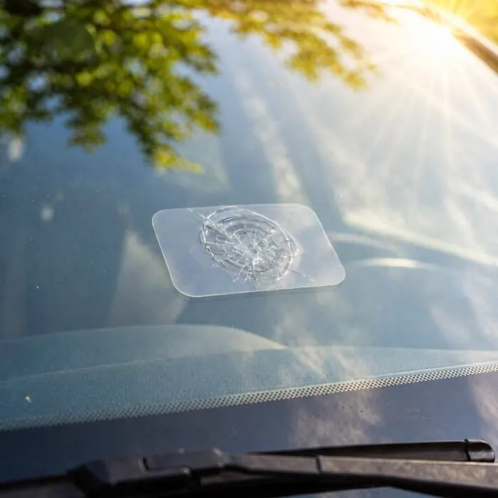 Clear curing film over a repaired windshield chip in direct sunlight